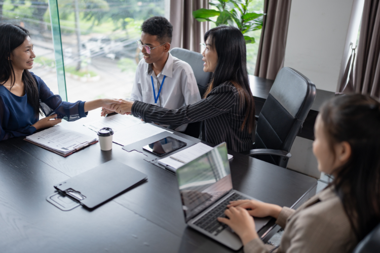 Professional office meeting where a woman greets a client with a handshake.
