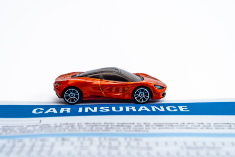Red model car displayed above paperwork related to car insurance coverage.