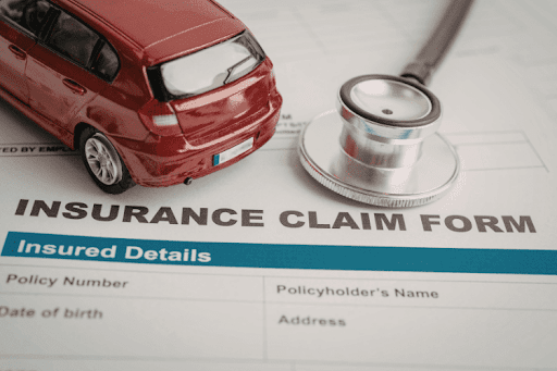 Red model car and stethoscope placed on an insurance claim form.