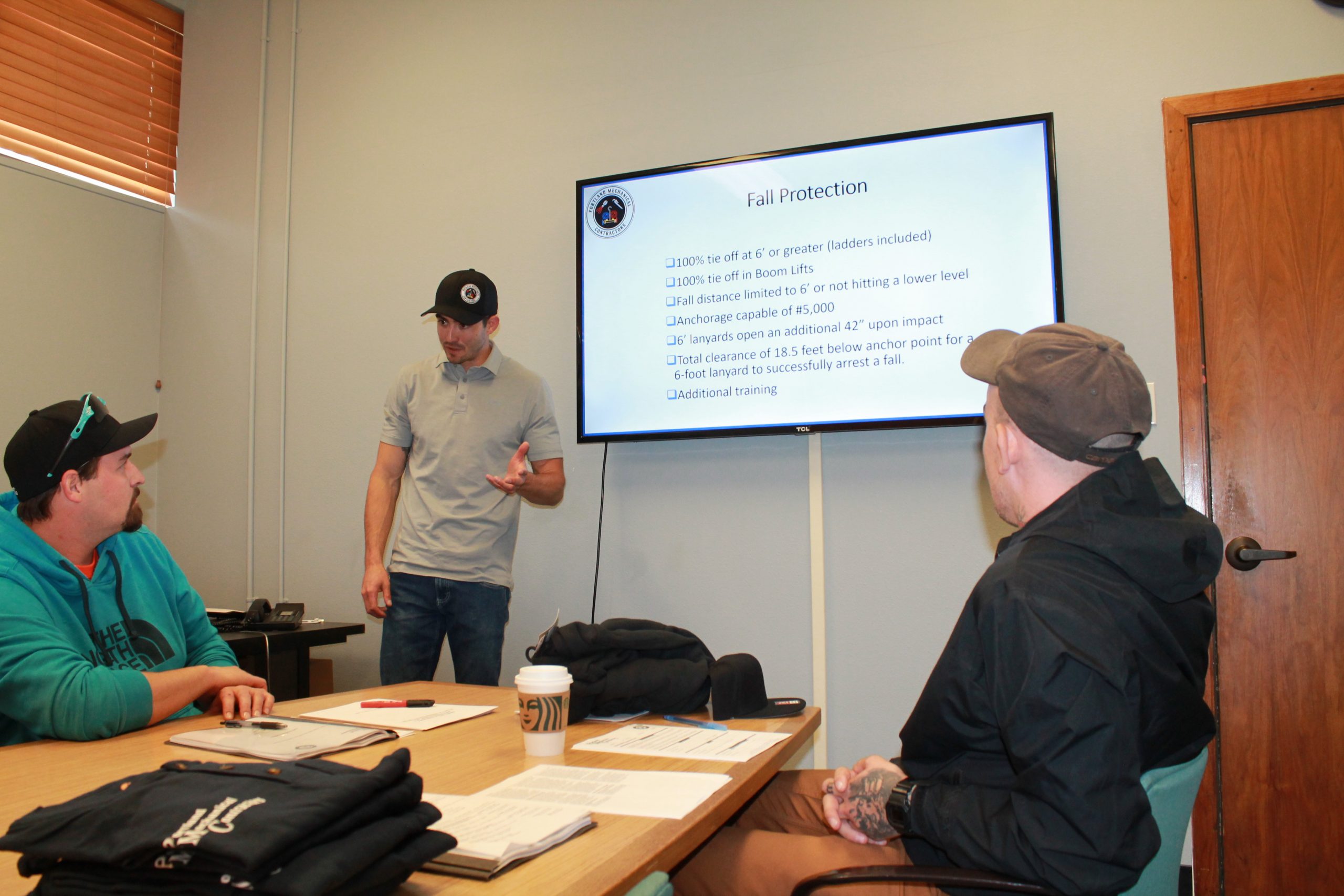 3 men discussing safety safety requirements with Powerpoint presentation