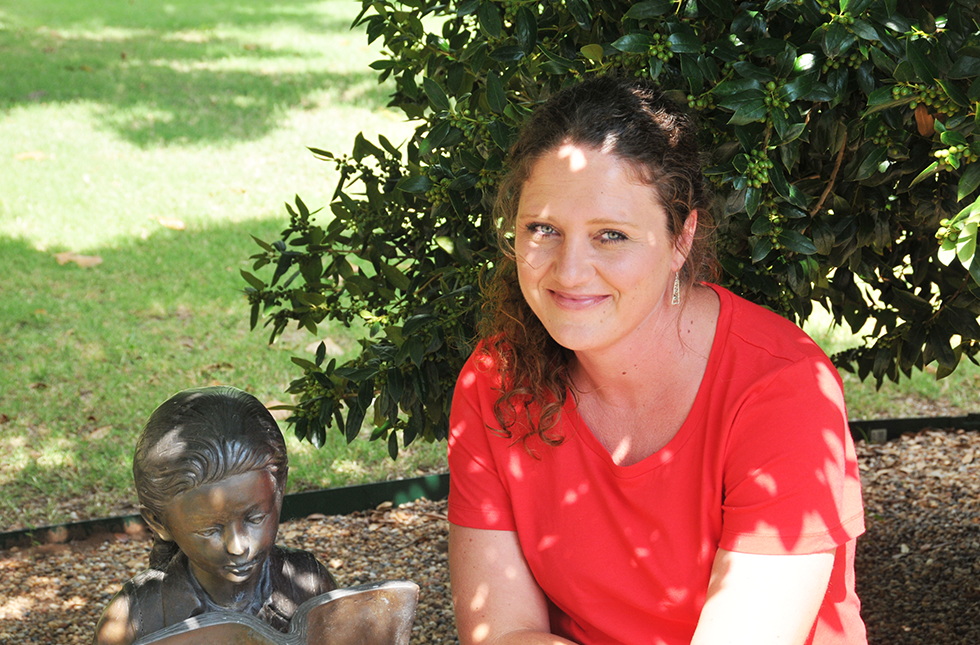Allison Hurst, psychology alumna, smiles in the shade of a tree.