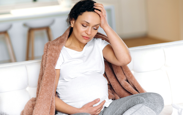 Pregnant woman feeling sick with a fever or headache