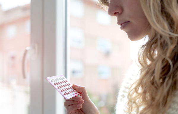 Young woman looking at birth control pills