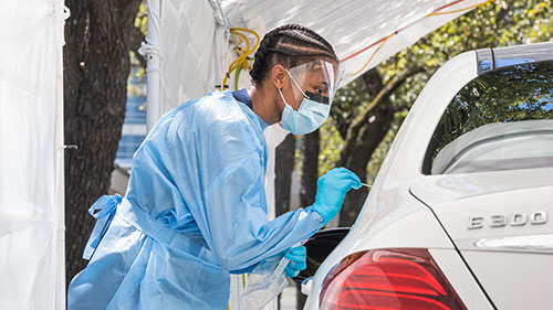 Doctor wearing PPE to take patient samples at a COVID-19 drive-thru testing center