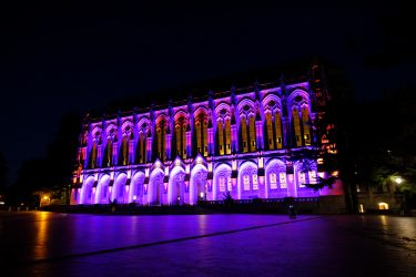 Suzzallo Library at night lit with purple and gold