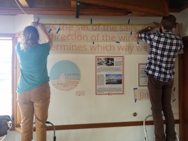 Samuel and Mica Low (class of 2018) applying vinyl lettering for the Still Afloat exhibit at CWB. Photo courtesy of Amy Gorton.