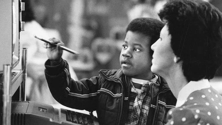 African American boy pointing_at_computer_monitor Helping One Student to Succeed HOSTS Corporation Vancouver Washington 1985