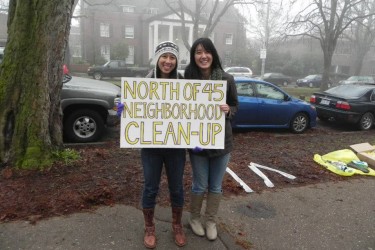 Students holding "neighborhood cleanup" sign.