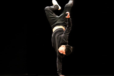 man standing on one hand with both legs in the air