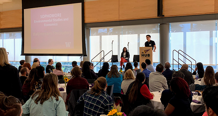 Baljaa speaking at a podium to a crowd of UW employees