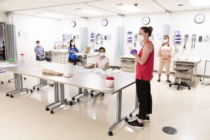 Students in a nursing simulation class spread out around the classroom to follow physical distancing guidelines