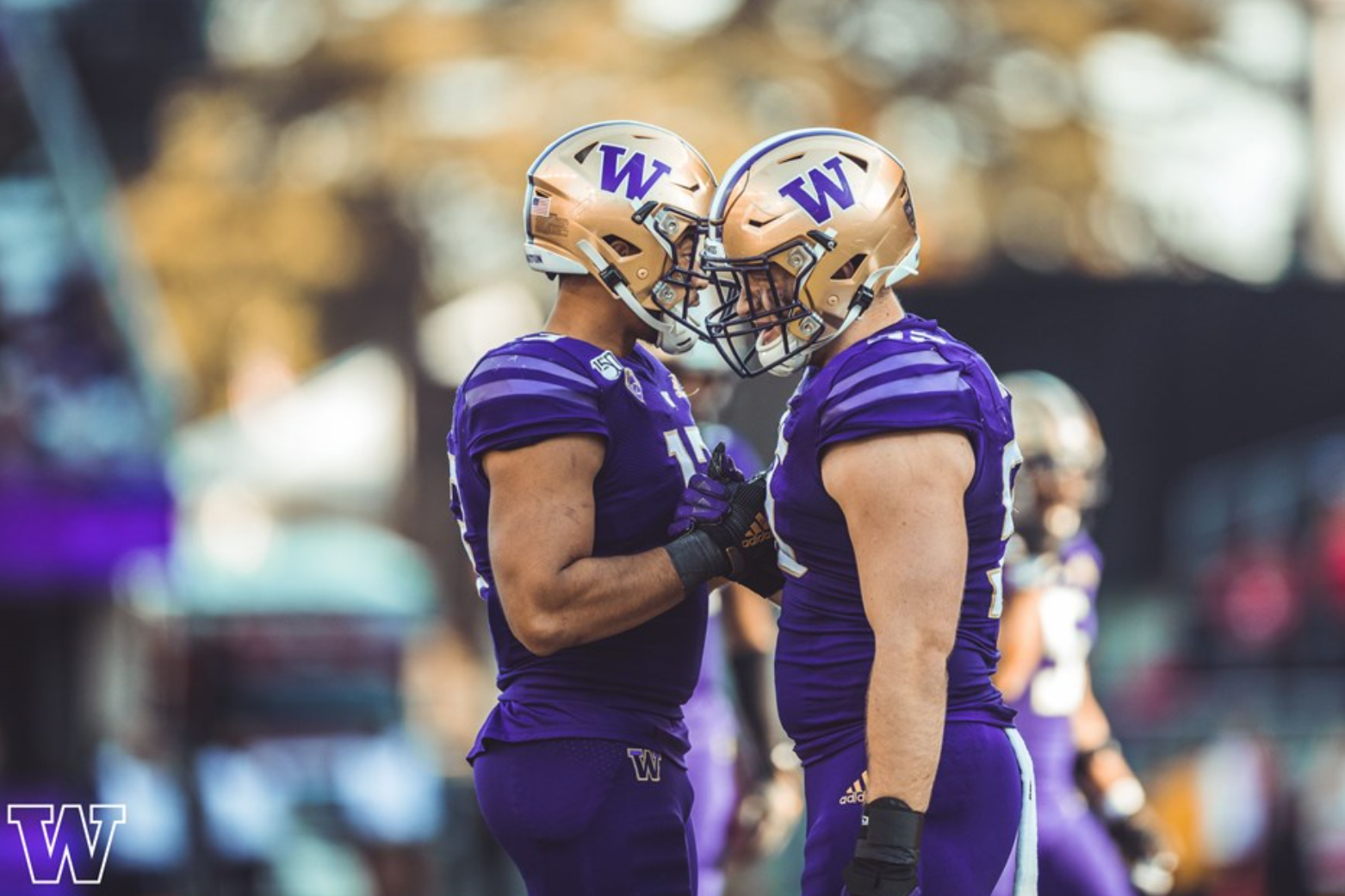 two University of Washington football players clasping hands