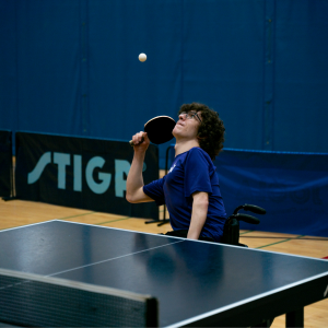 A table tennis player focuses on the ball while playing from a wheelchair as a part of our Rec Clubs.