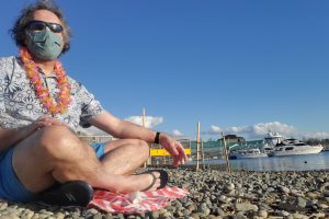 A team member of Teriyaki Donut dressed in Hawaiian attire sits at the Hedges Waterway Park.