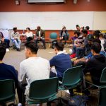 Group of young men of color sitting in a circle.