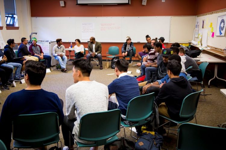 Group of young men of color sitting in a circle.