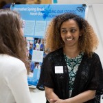 Student stands in front of her poster and explains her research