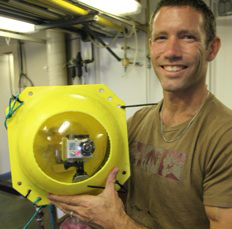 Matthew Alford holds the “crush cam” Matthew Alford holds the “crush cam,” a Go Pro camera housed inside a glass sphere able to withstand pressures deep in the ocean.