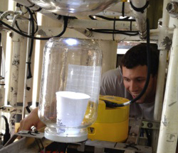 UW oceanography graduate student Kevin Tempest, adjusts a cup inside a clear cyclinder before it is sent to the seafloor alongside scientific instruments.