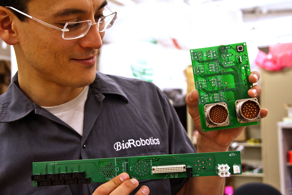 UW electrical engineering doctoral student Hawkeye King holds the circuit boards and connectors for the Raven II robot.