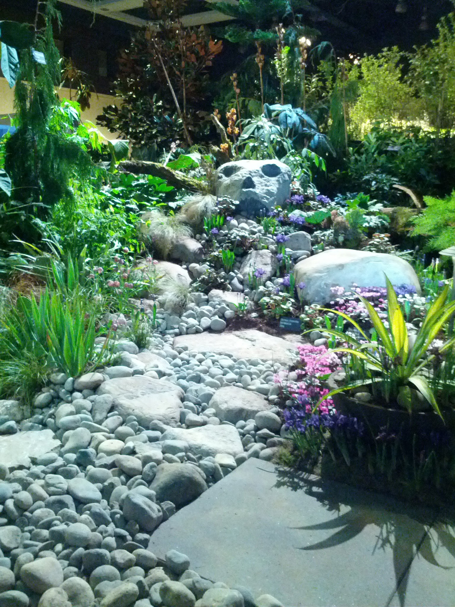 Plants, stone walkway and face of stone in garden