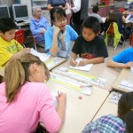 Four elementary students work at desk with UW undergraduate