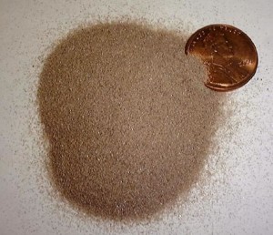 Pile of grains of zircon next to penny for size comparison