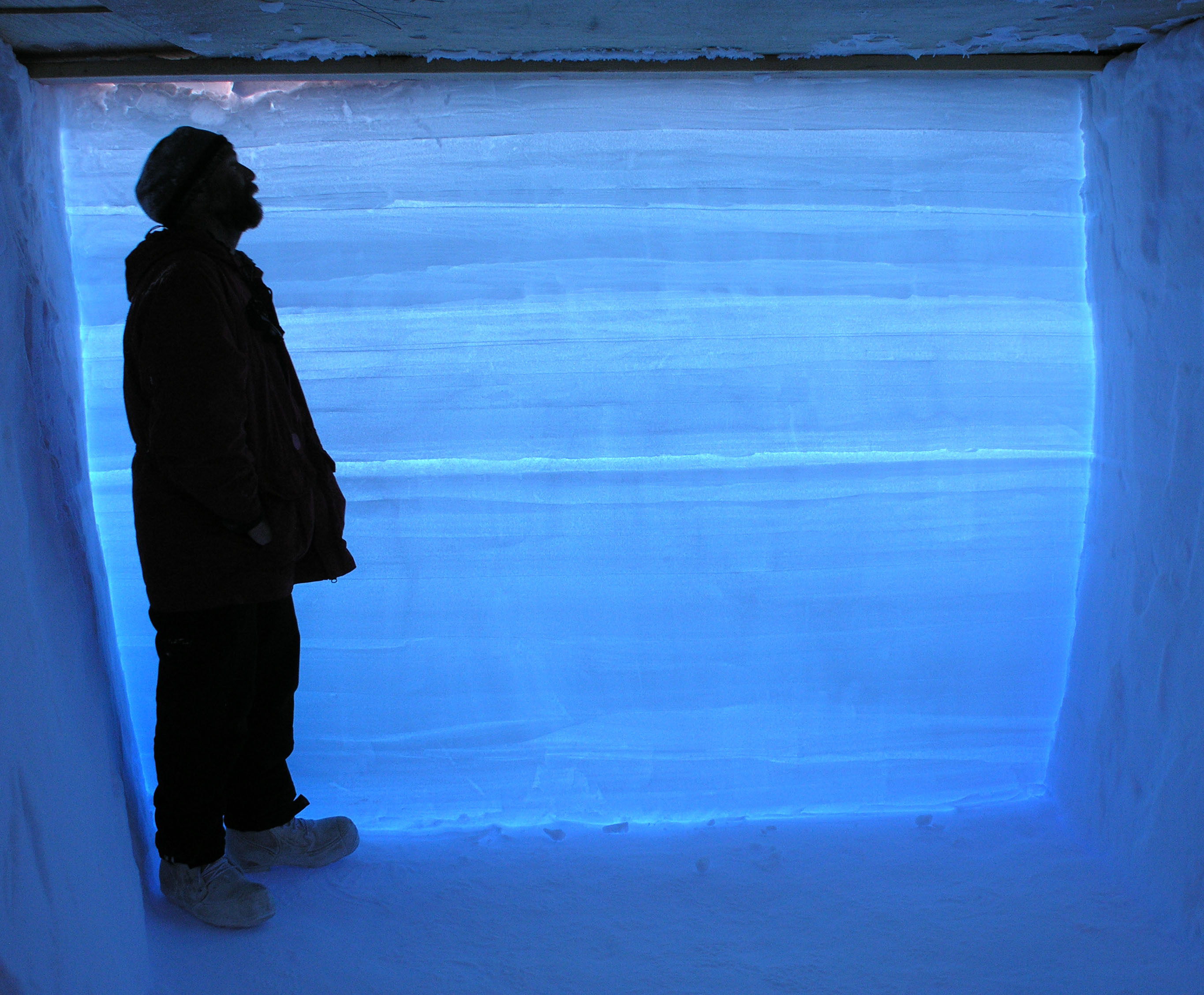A researcher stands in a snow pit next to an Antarctic ice core.