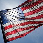 Sun shining through the U.S. flag, with a UW logo.