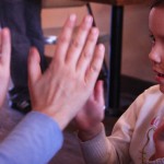 child plays pat-a-cake with an adult