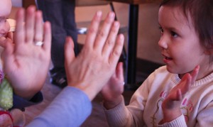 child plays pat-a-cake with an adult
