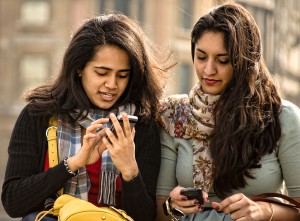 Two friends check their smartphones.