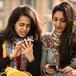 Two friends check their smartphones.