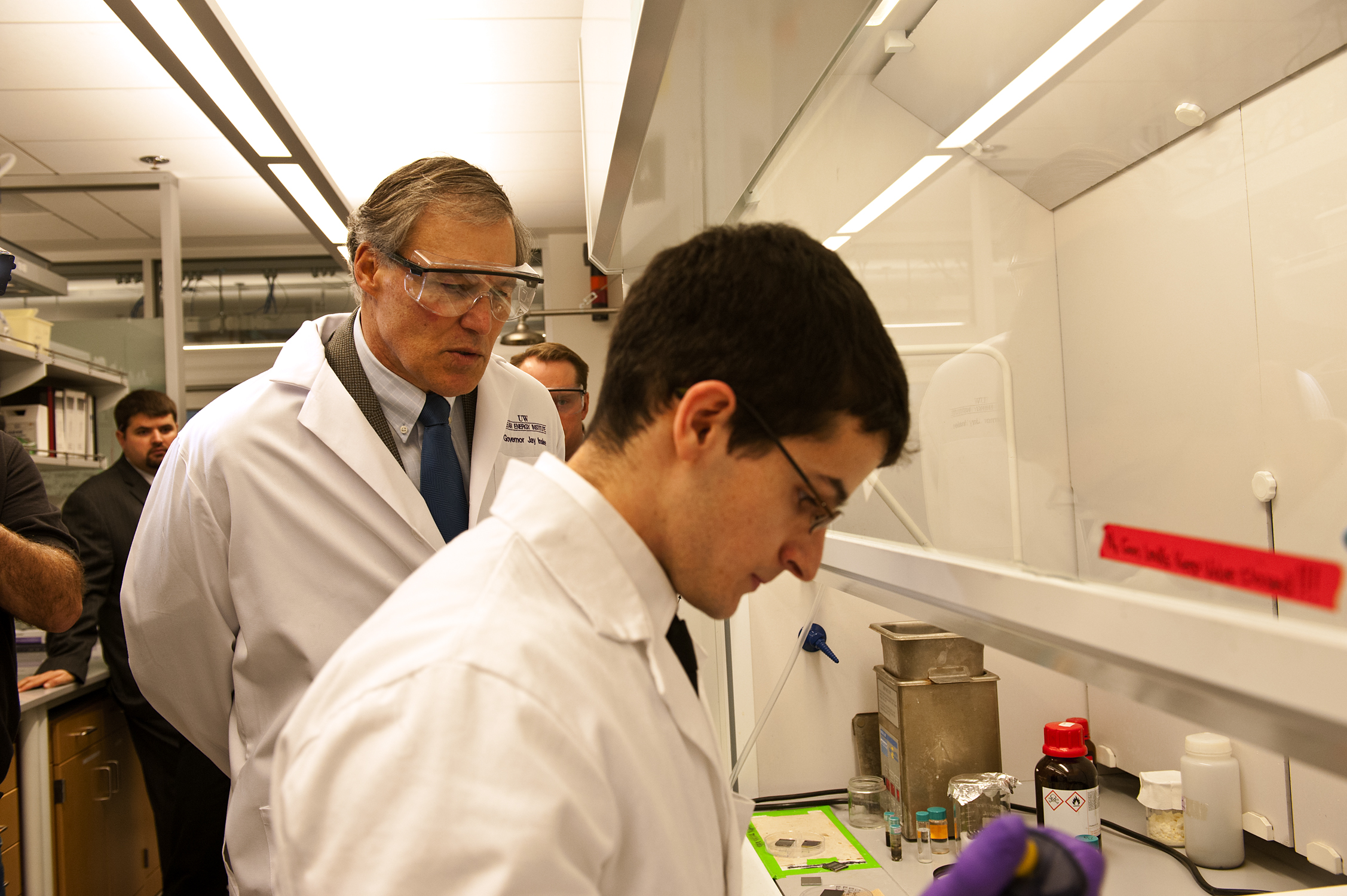 Gov. Jay Inslee watches as Wes Williamson, a UW chemical engineering graduate student, runs a demonstration in a lab.