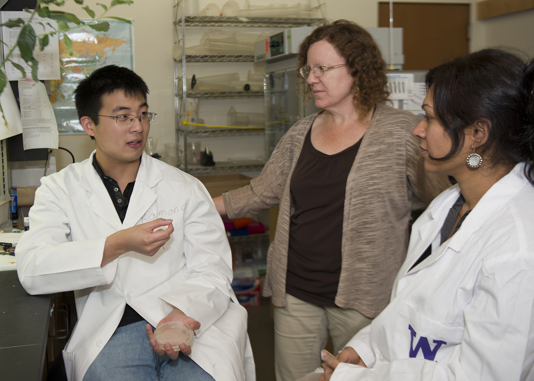 Three sit and stand in lab talking