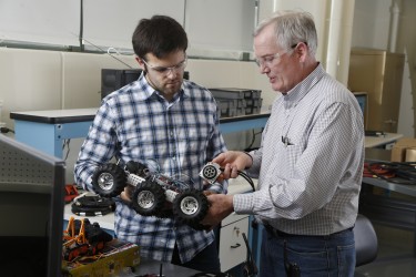 Benjamin Janicki, left, a UW graduate student, and Boeing engineer Jim Buttrick inspect a remotely operated vehicle that could be used to crawl inside small spaces in airplanes.
