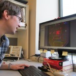 Jeffrey Herron reviews a circuit board he designed to allow for wireless and mobile experiments with the Activa PC+S Deep Brain Stimulation system.