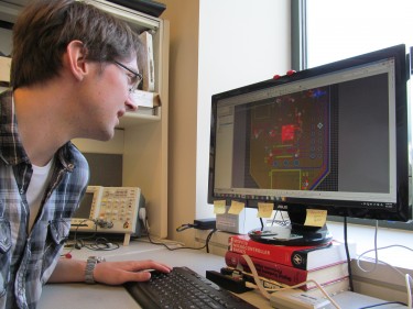Jeffrey Herron reviews a circuit board he designed to allow for wireless and mobile experiments with the Activa PC+S Deep Brain Stimulation system.