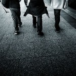 Black and white image shot from the back of three boys walking.