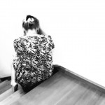 Black and white photo of woman sitting alone on stairs