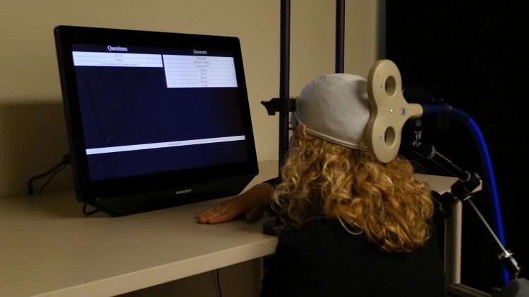 University of Washington postdoctoral student Caitlin Hudac wears a cap that uses transcranial magnetic stimulation (TMG) to deliver brain signals from the other participant.