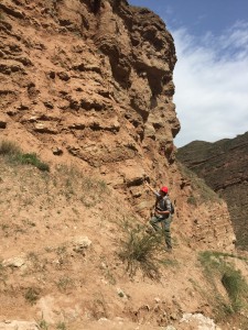 person pointing at sandy cliff