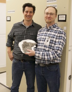 Two men posing with a fossil they discovered.