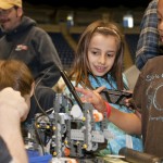 A young girl takes notice of a robot project at a college event promoting science to children.