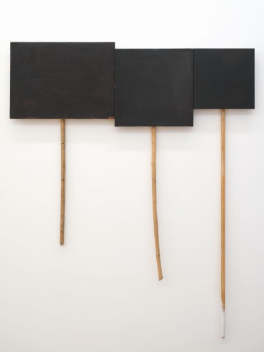 "3 Panel Glyph #2," oil on canvas on panel and sticks, by UW professor Denzil Hurley, courtesy of the artist and CANADA Gallery, New York. Part of an exhibit titled "Disclosures" at the Seattle Art Museum May 20 through November. The pieces depicted are black placard-like objects affixed to handle-like broomsticks.