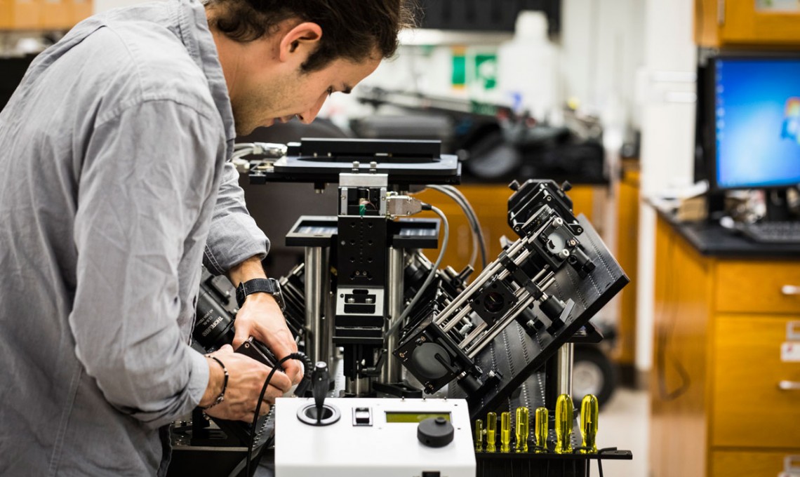 Photo of Adam Glaser tweaking microscope
