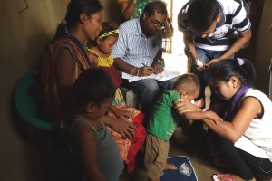 A group of people in a house, surrounding a scale.