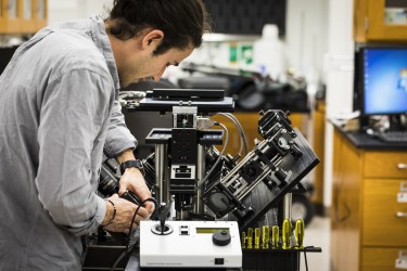 Photo of Adam Glaser tweaking microscope