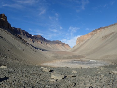 pond in bare valley with blue sky