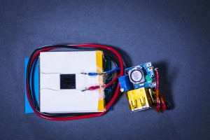 The UW team's prototype heatsink assembly, which can be attached to the back of a smartphone, consists of a photovoltaic cell (silver square, top) attached to a thermoelectric generator (in white). The generator is mounted on top of an aluminum heatsink. The entire assembly is only 8mm thick and 40mm wide.